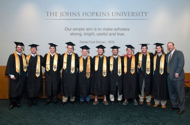 Photo of thirteen Johns Hopkins senior athletes receiving their diplomas during a special ceremony.